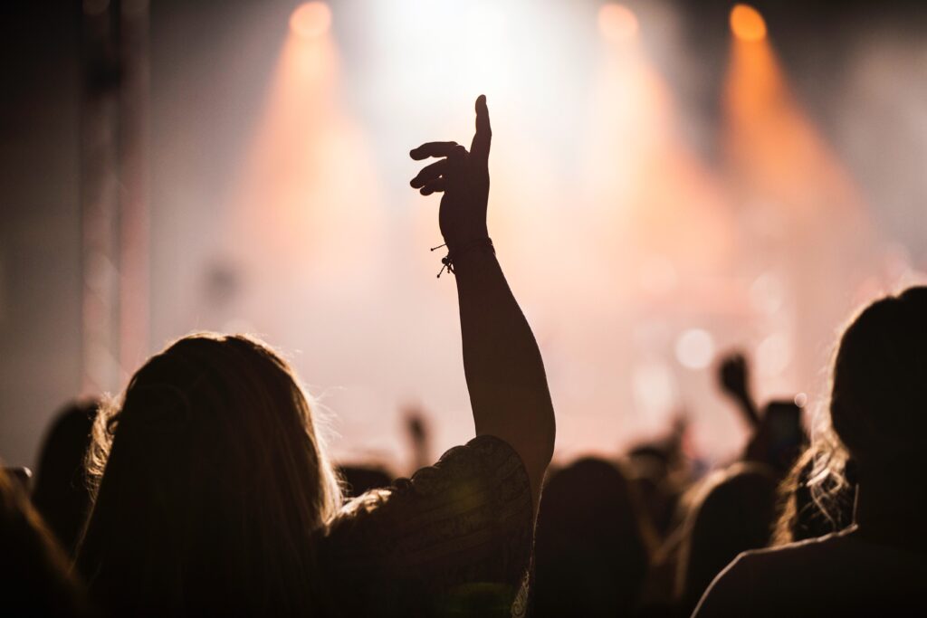 Publik framför en belyst scen. Några har händerna i luften.